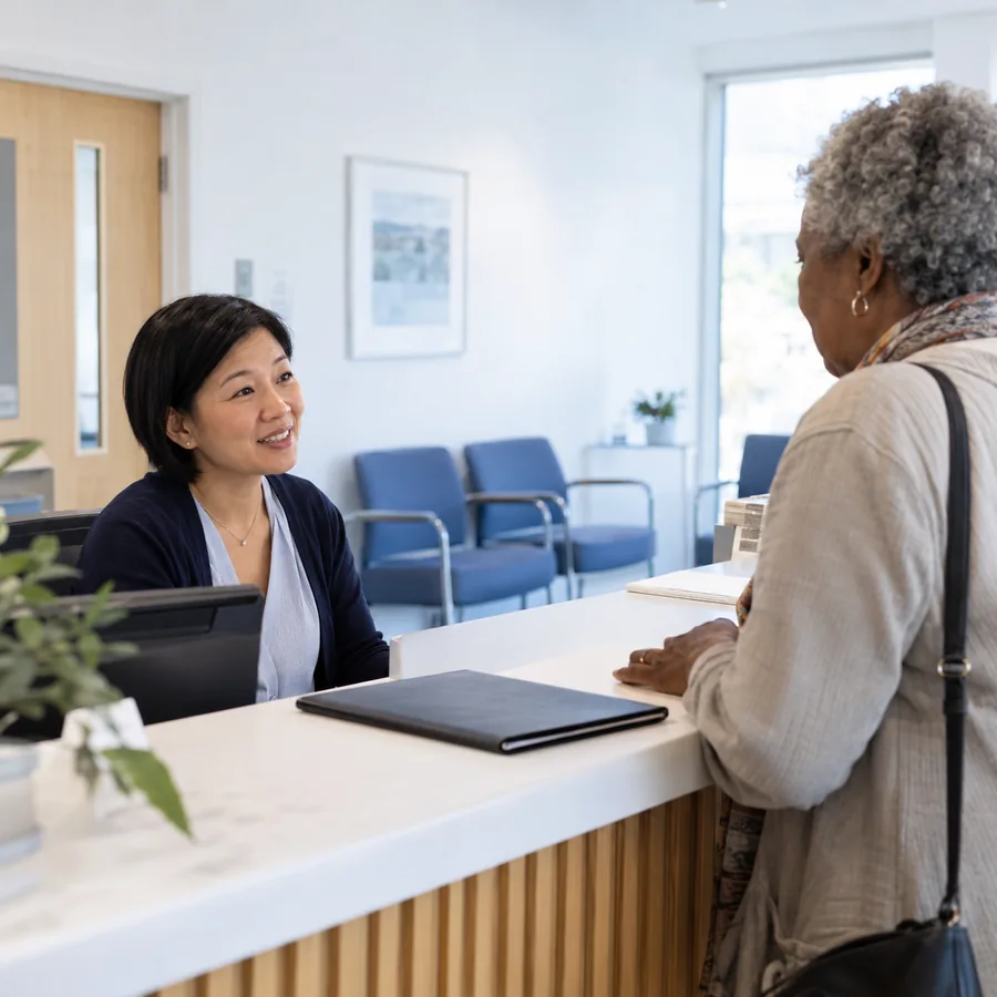Clinic receptionist welcoming a visitor in a waiting area