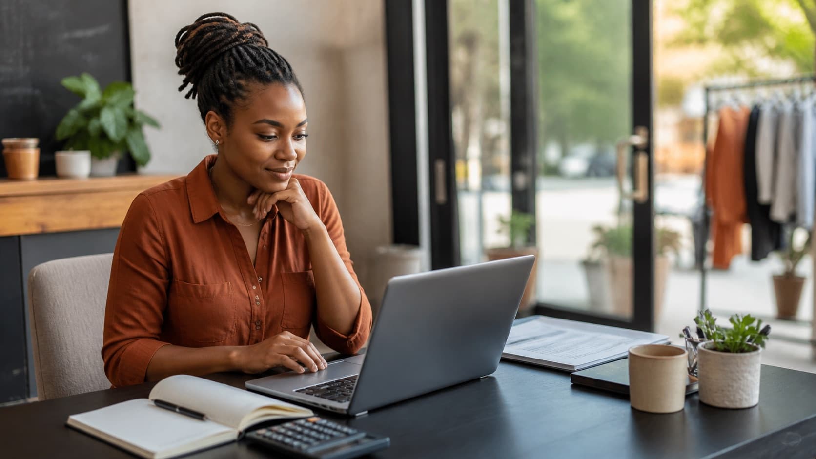 Small business owner comparing review management software costs at a worktable