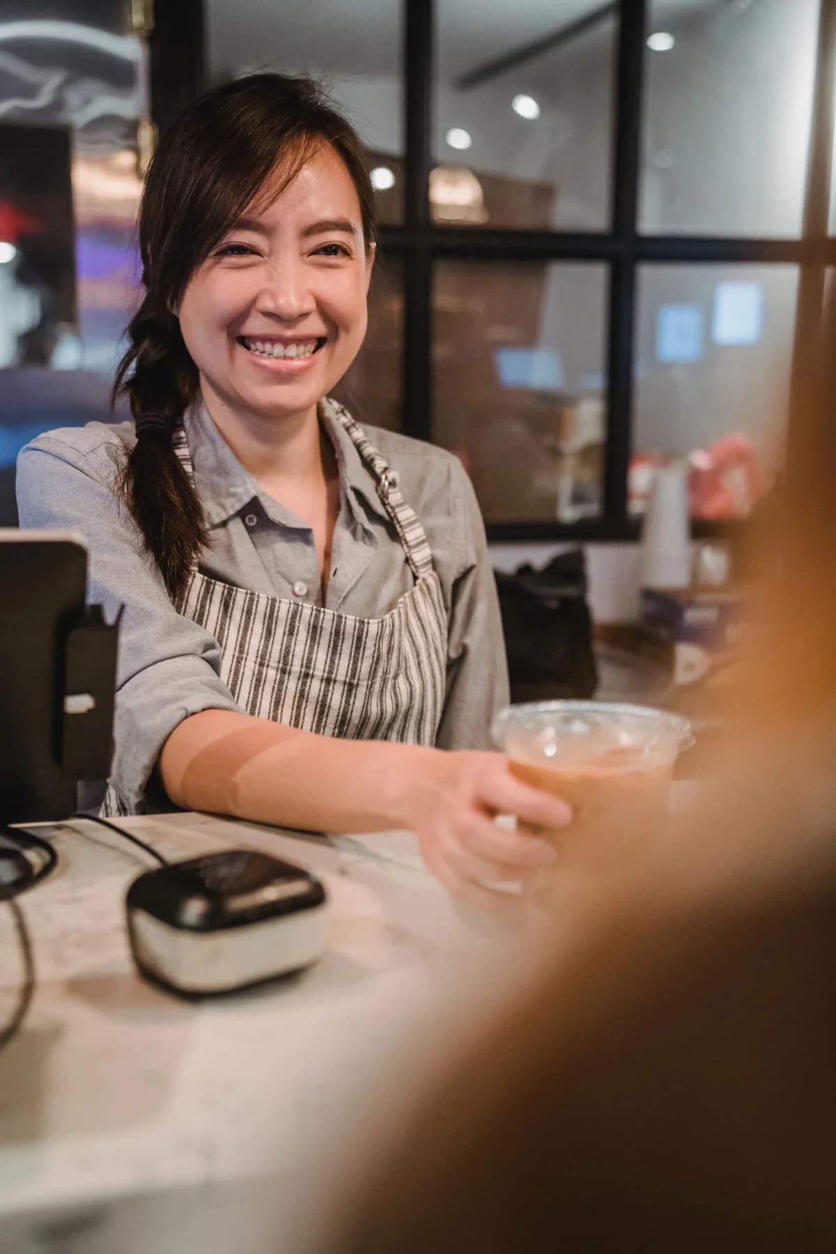 A barista serving iced coffee to a customer